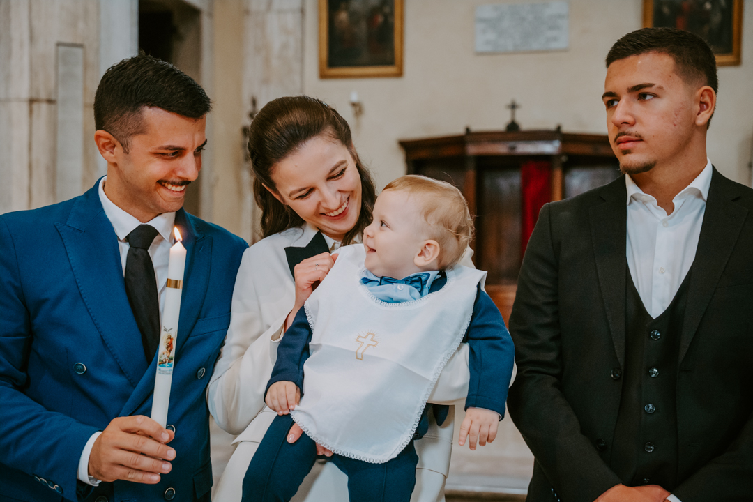 Servizio fotografico battesimo famiglia Trieste - ritratto genitori con bambino all'esterno chiesa
