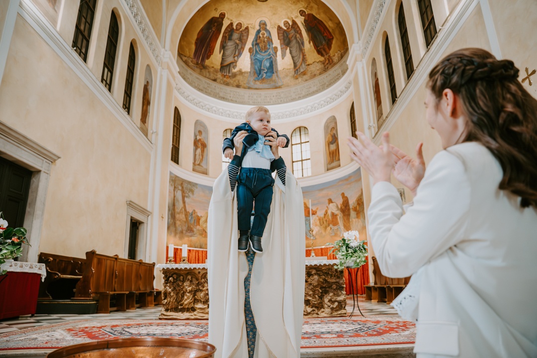 Servizio fotografico battesimo famiglia Trieste - ritratto genitori con bambino all'esterno chiesa